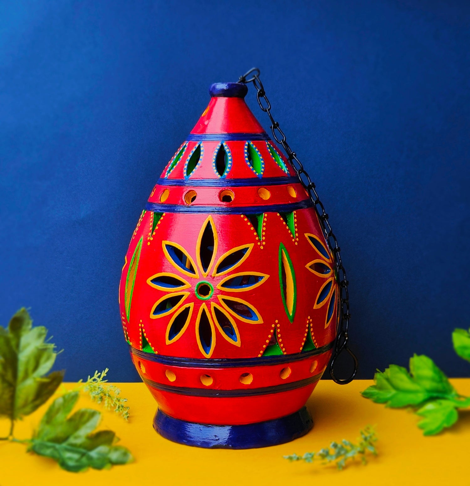 Scarlet red terracotta lamp with flower shape cut in it.